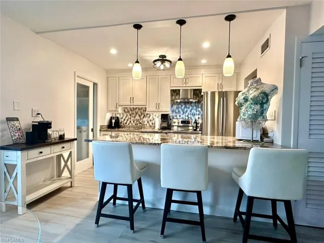 Kitchen with granite stone counters, a kitchen breakfast bar, freestanding refrigerator, and oversized Island