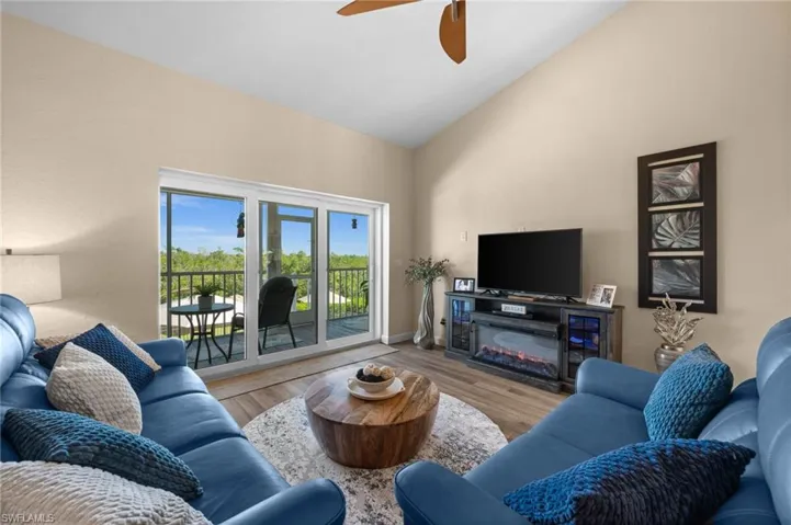 Living area with wood finished floors, ceiling fan, and high vaulted ceiling