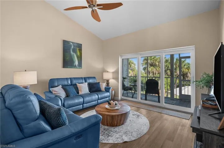 Living area with wood finished floors, high vaulted ceiling, and a ceiling fan
