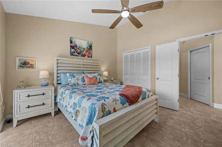 Bedroom with high vaulted ceiling, a ceiling fan, a closet, and light tile patterned floors