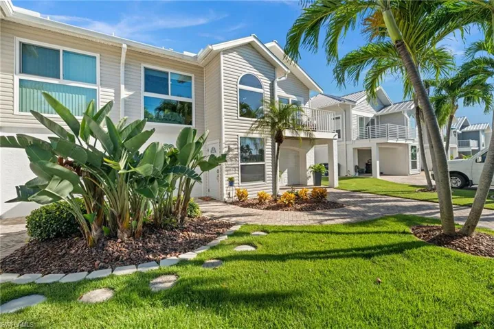 View of front of house with a front lawn, a balcony, decorative driveway, and a residential view