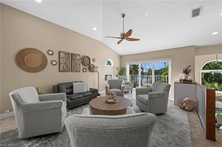 Living room featuring vaulted ceiling, recessed lighting, a ceiling fan, and a water view