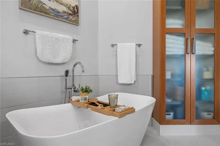 Full bath with a freestanding tub, tile walls, wainscoting, and tile patterned floors
