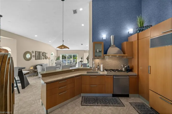 Kitchen featuring a peninsula, decorative light fixtures, dark stone countertops, lofted ceiling, and appliances with stainless steel finishes