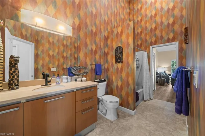 Full bathroom with vanity, shower / bath combo with shower curtain, and light tile patterned floors