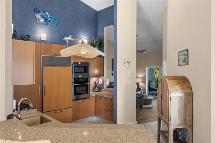 Kitchen featuring built in appliances, light stone counters, modern cabinets, and light wood-style floors