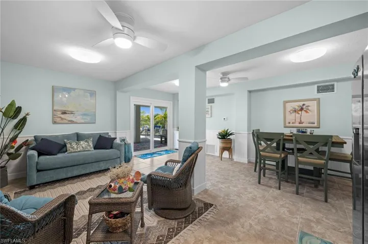 Living room featuring ceiling fan, wainscoting, and light tile patterned floors
