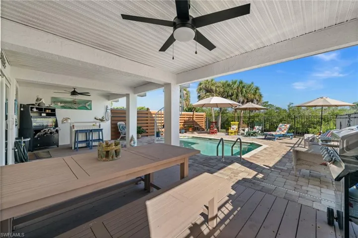 View of pool with a patio area, ceiling fan, a wooden deck, a fenced backyard, and outdoor dining area