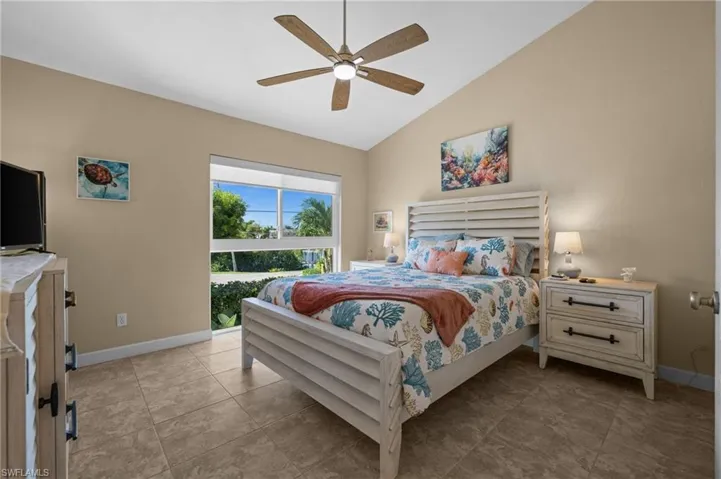 Bedroom featuring vaulted ceiling, ceiling fan, and light tile patterned floors