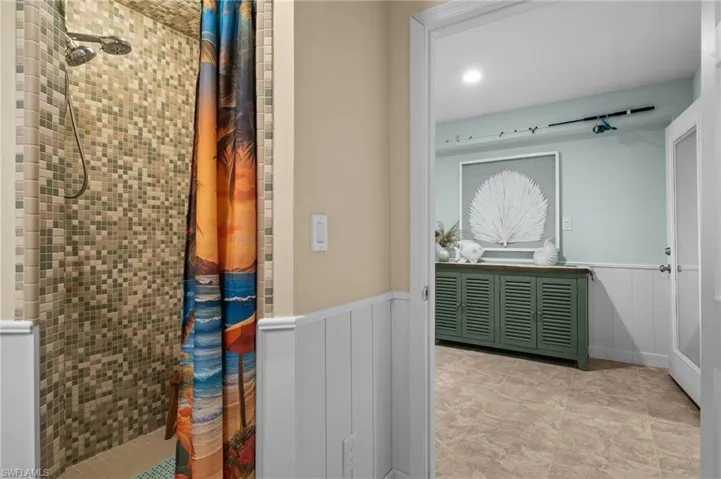 Full bathroom featuring a stall shower and a wainscoted wall