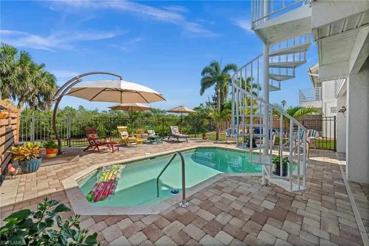 View of swimming pool with a patio area, a balcony, stairway, and a fenced backyard