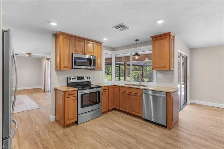 Kitchen with stainless steel appliances, light wood-style floors, brown cabinets, and recessed lighting