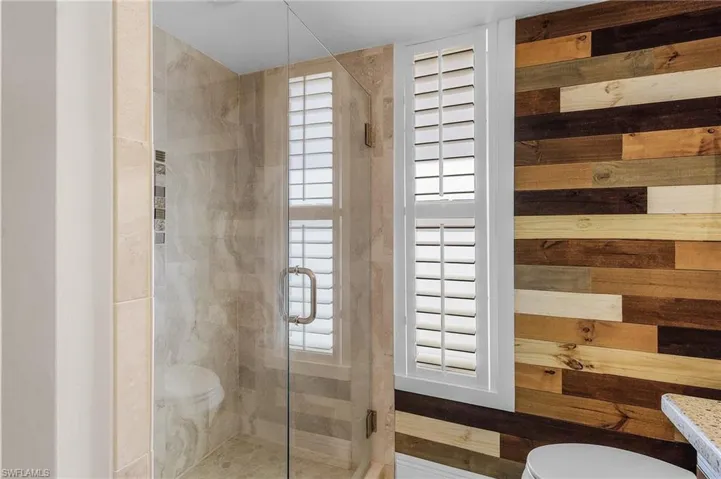 Bathroom featuring a shower stall, wood walls, and vanity