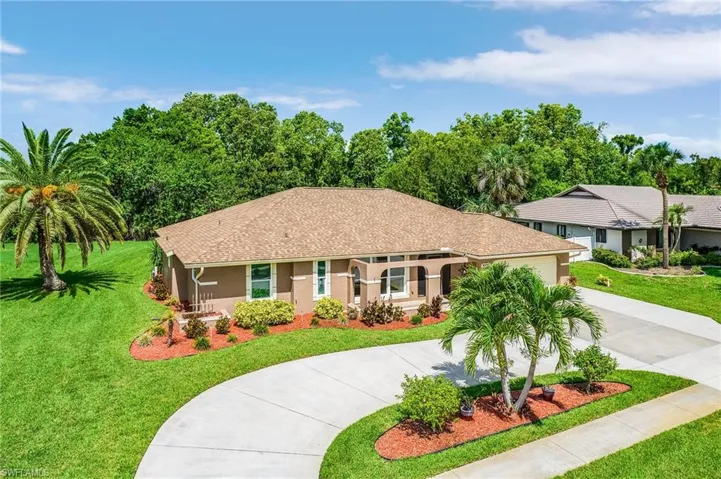 Single story home with curved driveway, a front lawn, a garage, and stucco siding