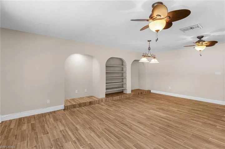 Spare room featuring ceiling fan, built in features, arched walkways, and light wood finished floors