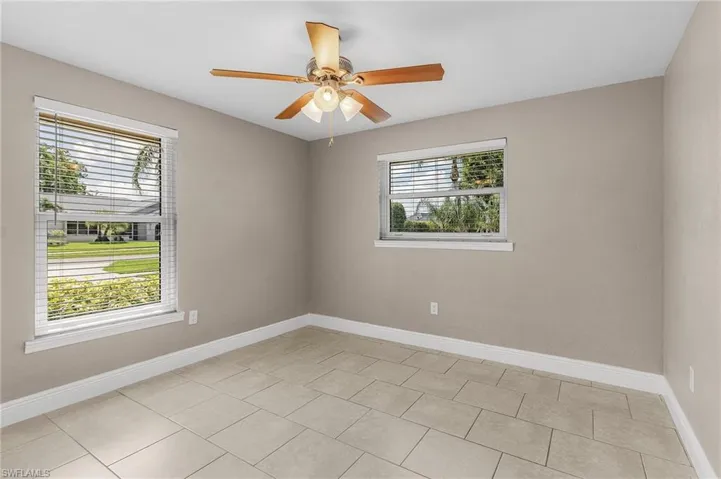 Spare room with plenty of natural light, a ceiling fan, and light tile patterned floors