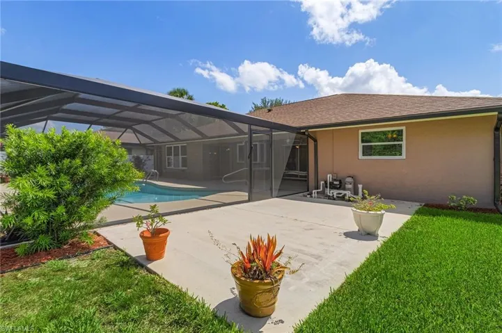 Rear view of house featuring stucco siding, a patio, an outdoor pool, a yard, and glass enclosure