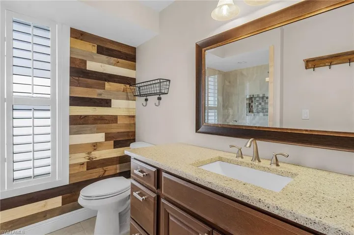 Bathroom featuring wood walls, vanity, a tile shower, tile patterned floors, and plenty of natural light