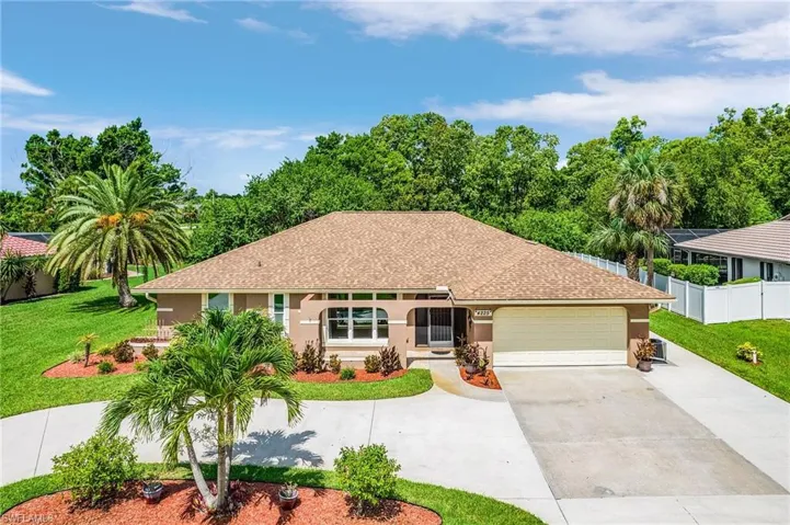 Ranch-style home with a garage, a shingled roof, driveway, and stucco siding