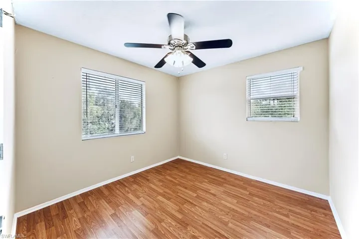 Empty room featuring hardwood / wood-style flooring, a wealth of natural light, and ceiling fan