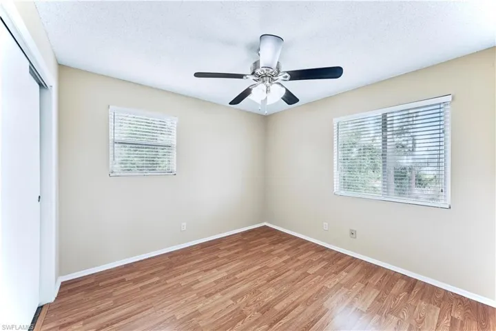 Unfurnished room with hardwood / wood-style floors, ceiling fan, plenty of natural light, and a textured ceiling