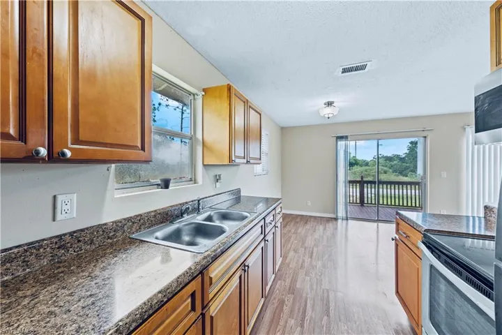 Kitchen featuring stainless steel electric range oven, light hardwood / wood-style floors, a textured ceiling, and sink