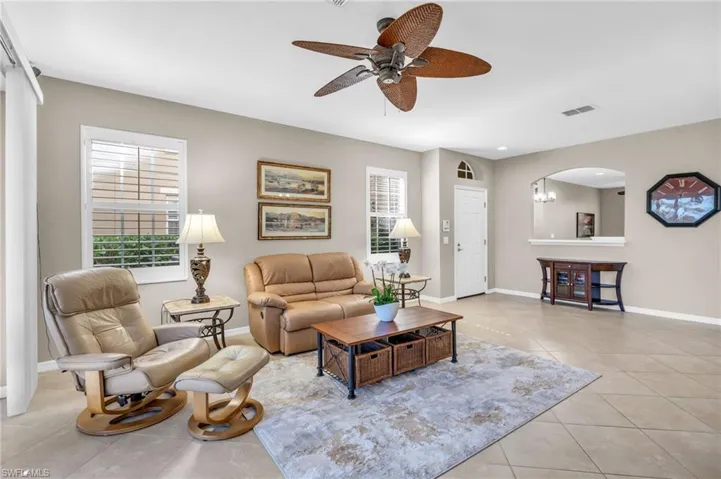 Living area with light tile patterned floors, ceiling fan, and arched walkways