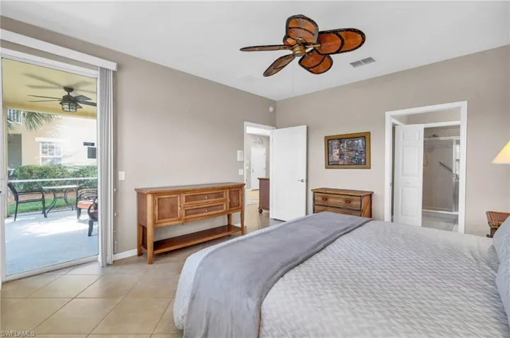 Bedroom featuring access to exterior, light tile patterned floors, ceiling fan, and ensuite bathroom