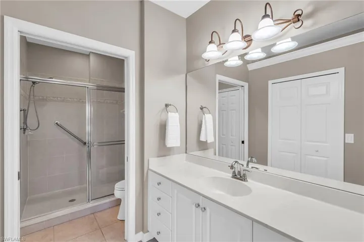 Bathroom featuring a shower stall, vanity, tile patterned flooring, a closet, and a chandelier