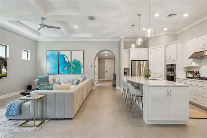 Living room with beamed ceiling, ceiling fan, crown molding, coffered ceiling, and sink