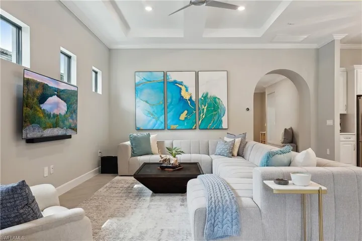 Living room featuring ornamental molding, light tile patterned floors, and ceiling fan