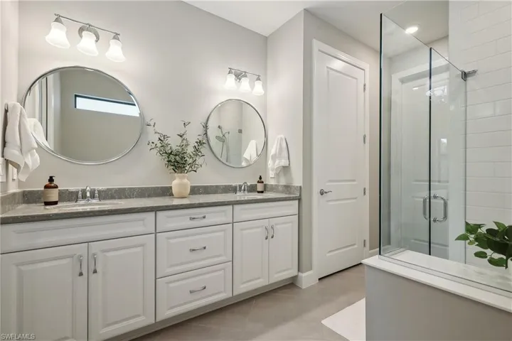 Bathroom with tile patterned flooring, a shower with door, and vanity