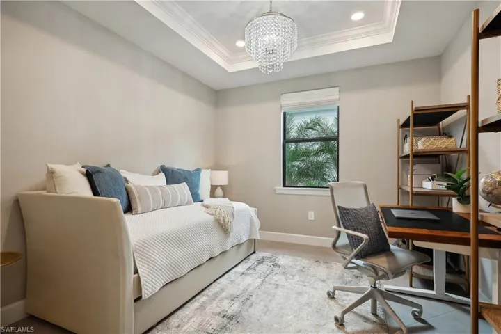 Bedroom featuring ornamental molding, a tray ceiling, and a chandelier