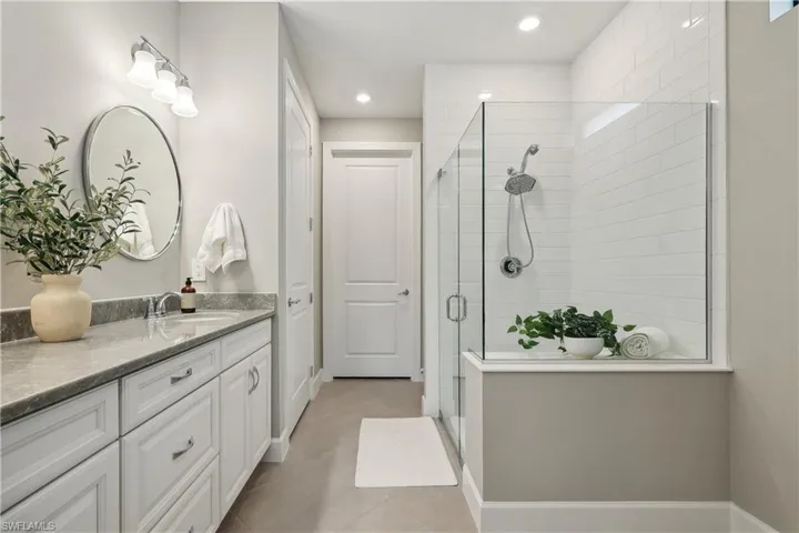 Bathroom featuring tile patterned flooring, a shower with shower door, and vanity