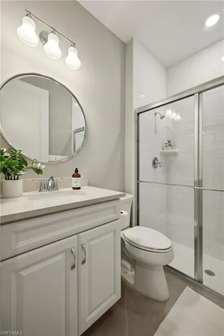 Bathroom with vanity, a shower with shower door, and toilet