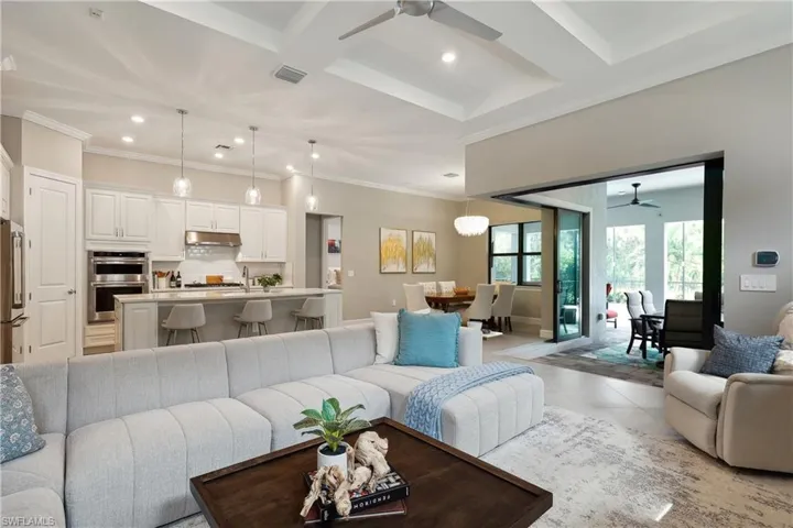 Tiled living room featuring ornamental molding, coffered ceiling, and ceiling fan