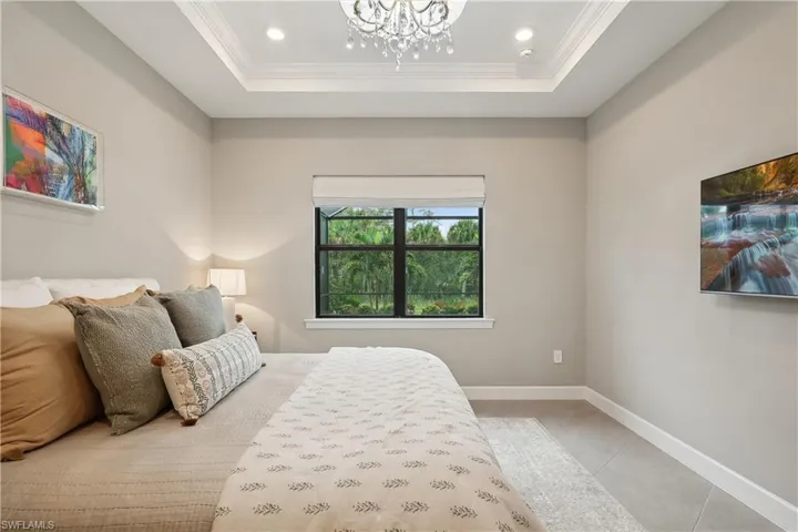 Tiled bedroom featuring ornamental molding, a chandelier, and a raised ceiling