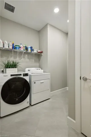 Washroom with light tile patterned flooring and independent washer and dryer
