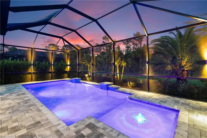 Pool at dusk featuring a lanai, pool water feature, and a patio area