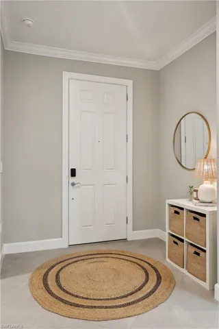 Tiled foyer featuring ornamental molding