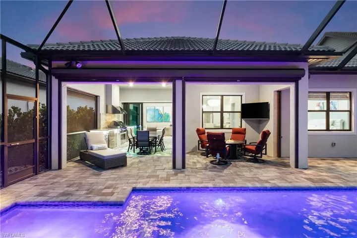 Back house at dusk featuring a patio and a lanai