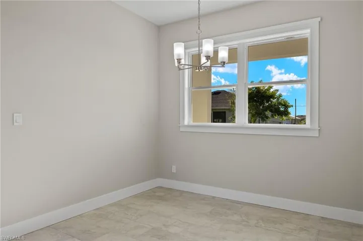 Empty room featuring light tile patterned floors and a chandelier