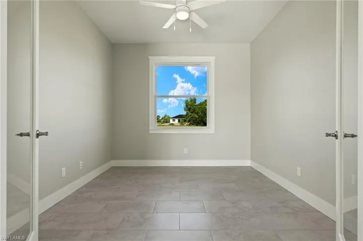 Tiled spare room with ceiling fan and french doors