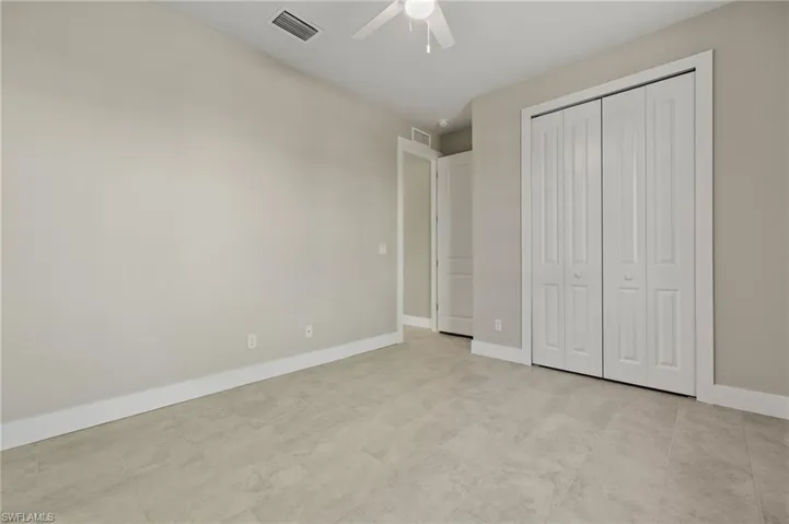 Unfurnished bedroom with ceiling fan, a closet, and light tile patterned flooring
