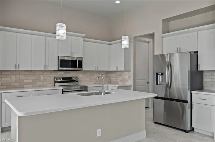 Kitchen with sink, decorative backsplash, an island with sink, and stainless steel appliances