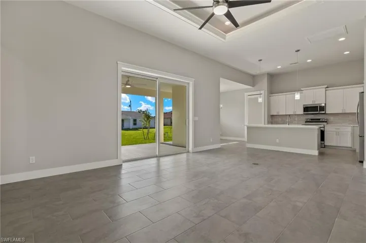 Unfurnished living room featuring ceiling fan, a raised ceiling, and light tile patterned flooring
