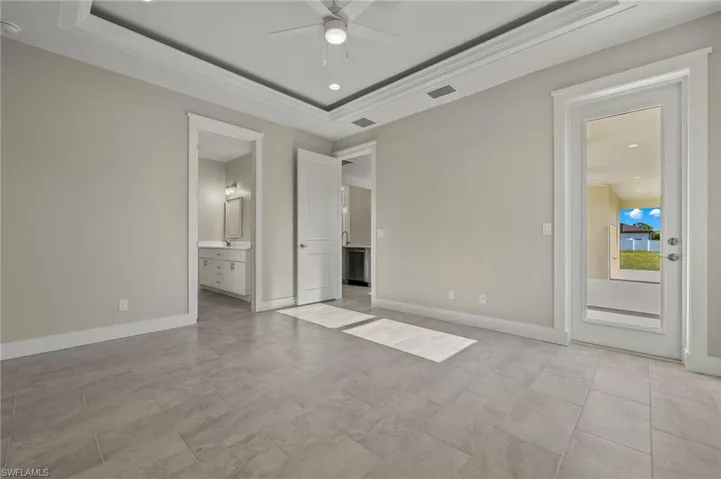 Unfurnished bedroom with a raised ceiling, light tile patterned floors, and ensuite bathroom
