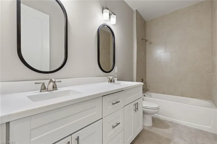 Full bathroom featuring tile patterned floors, vanity, tiled shower / bath combo, and toilet