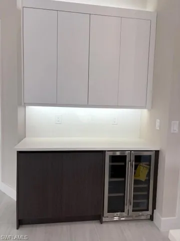 Bar featuring modern cabinets, beverage cooler, and light stone countertops