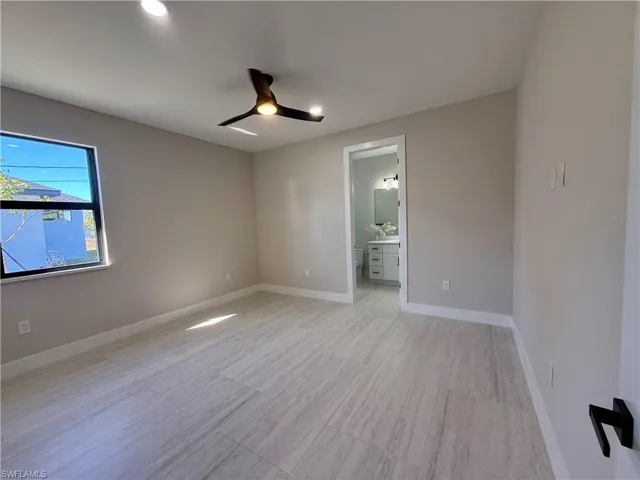 Unfurnished bedroom featuring a ceiling fan, ensuite bathroom, and light wood-type flooring